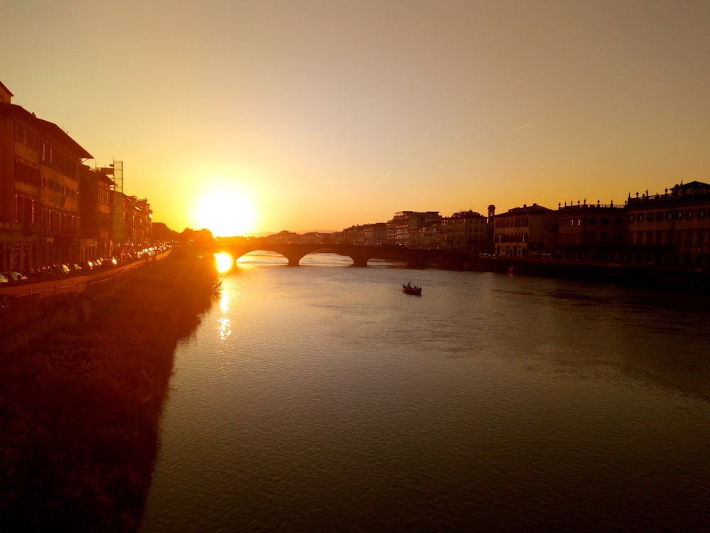 body of water near buildings during sunset