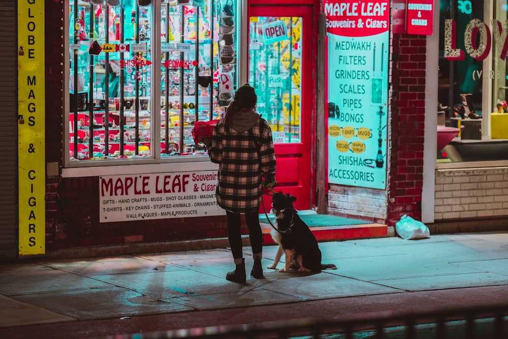 a woman standing on a sidewalk next to a dog