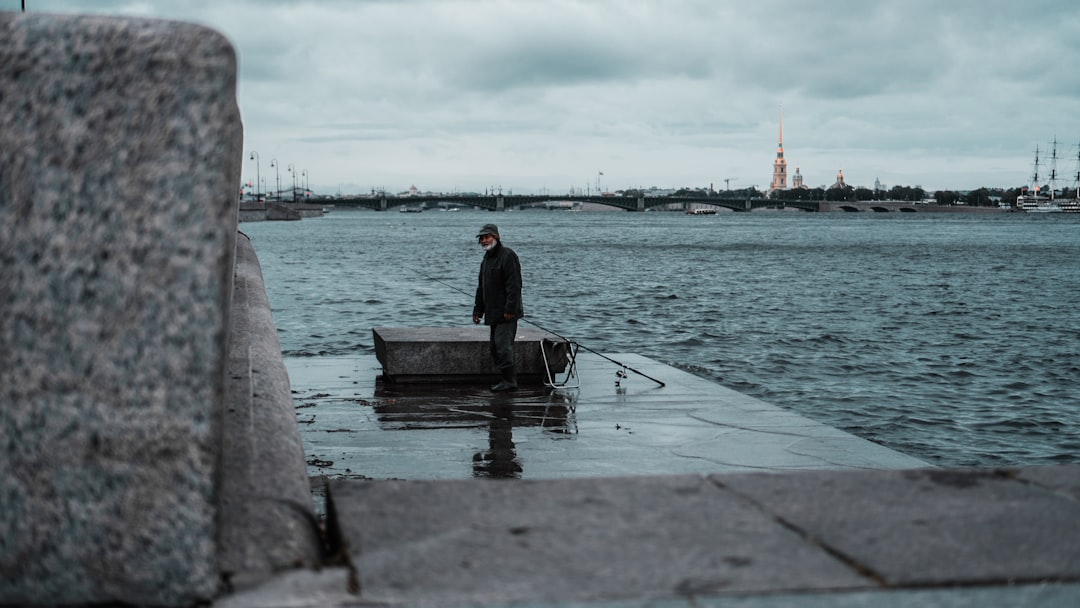 man in black jacket sitting on dock during daytime