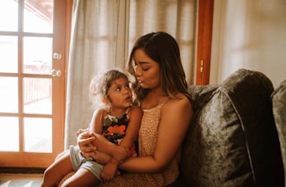 A parent calmly comforting a toddler during a tantrum in a warm, inviting living room