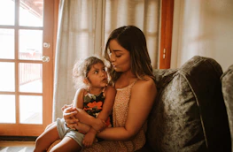 Two parents smiling warmly while co-parenting their child in a cozy home.