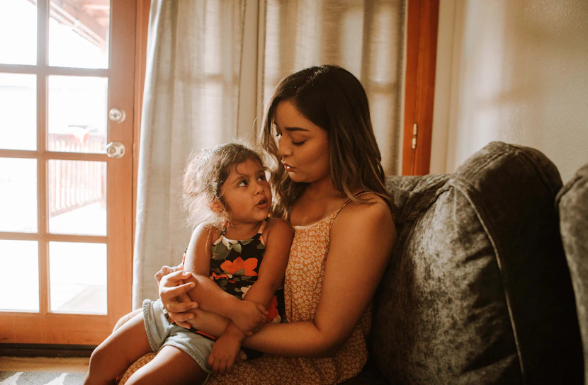 A caring mother gently soothing her toddler in a cozy living room.