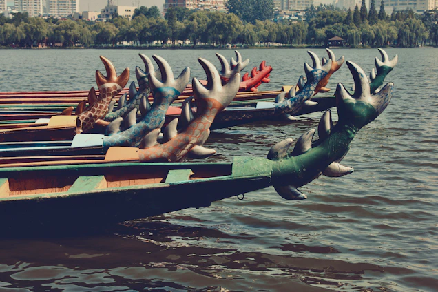 A vibrant dragon boat team paddling in perfect sync across shimmering water under a clear blue sky.