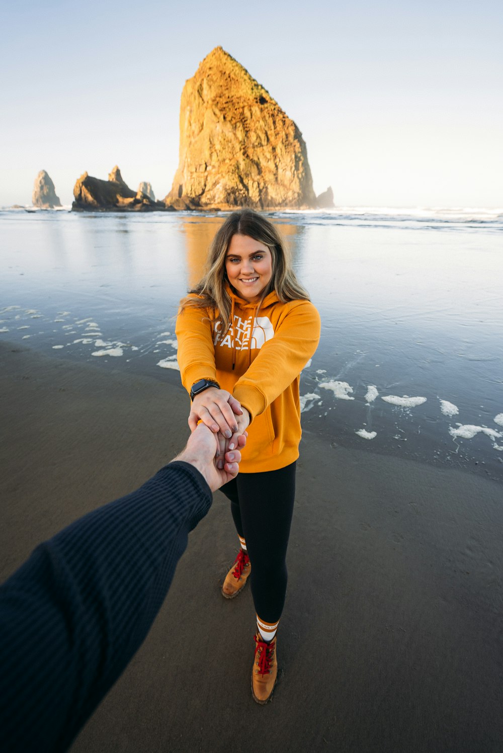 woman in yellow hoodie standing on beach shore during daytime