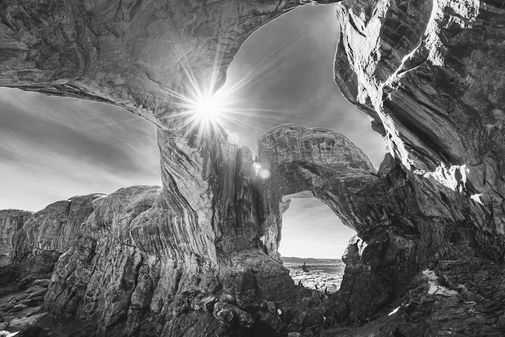 grayscale photo of rock formation near body of water