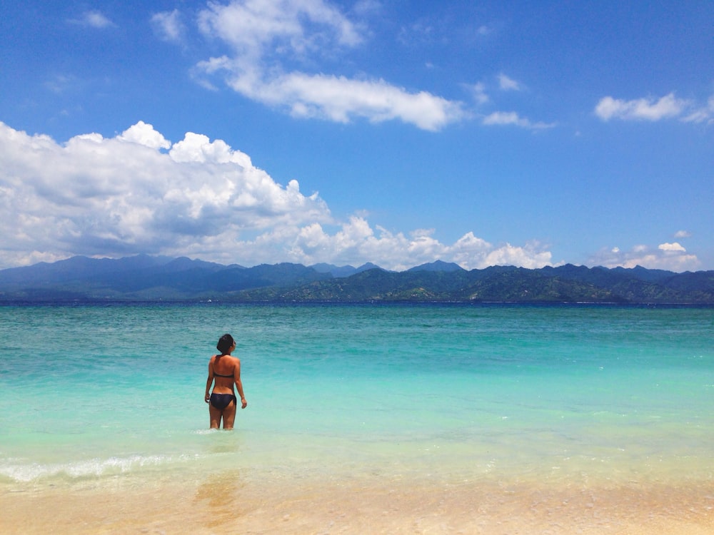 woman in black bikini standing on beach during daytime