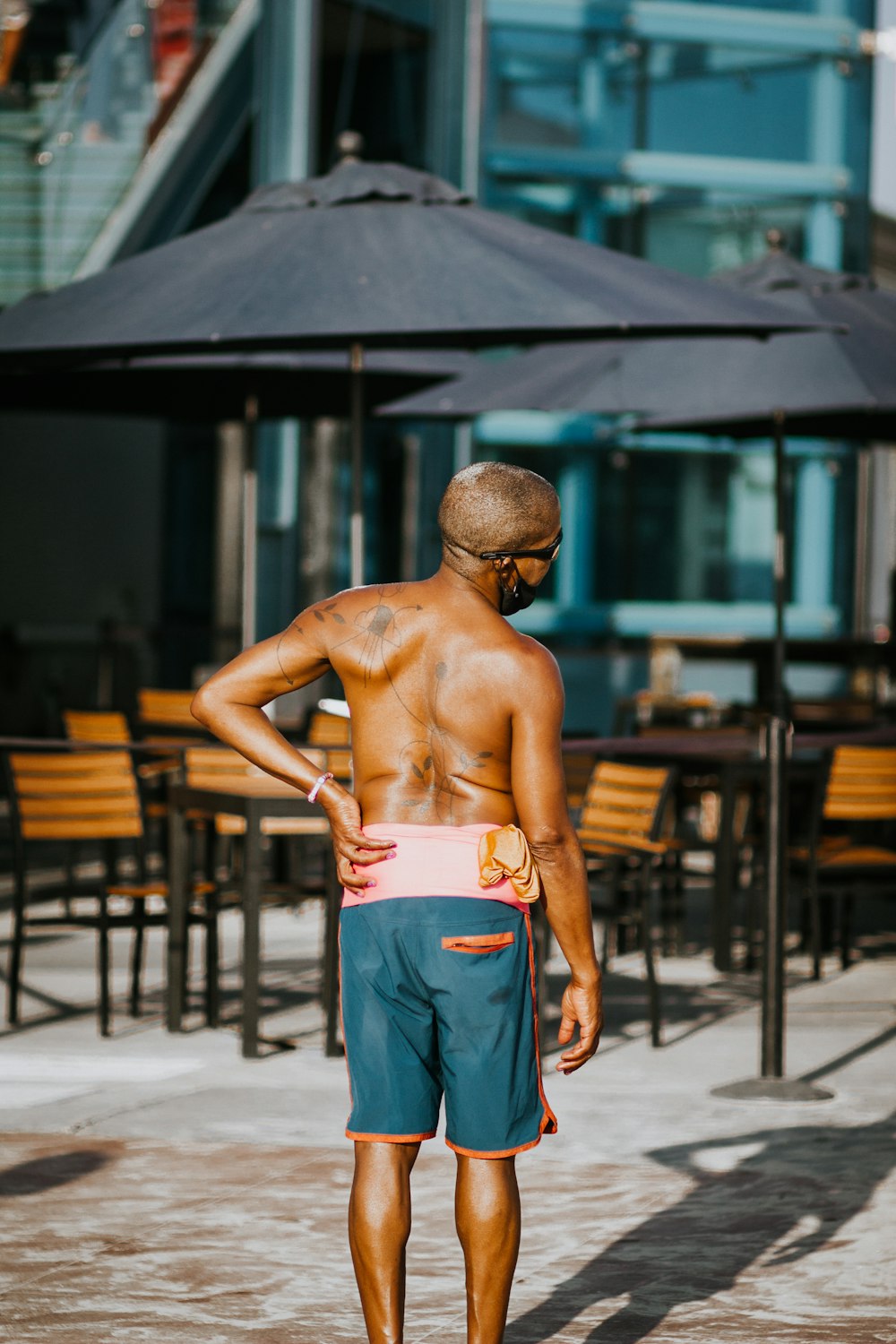 homme aux seins nus en jean bleu debout près d’une table en bois marron