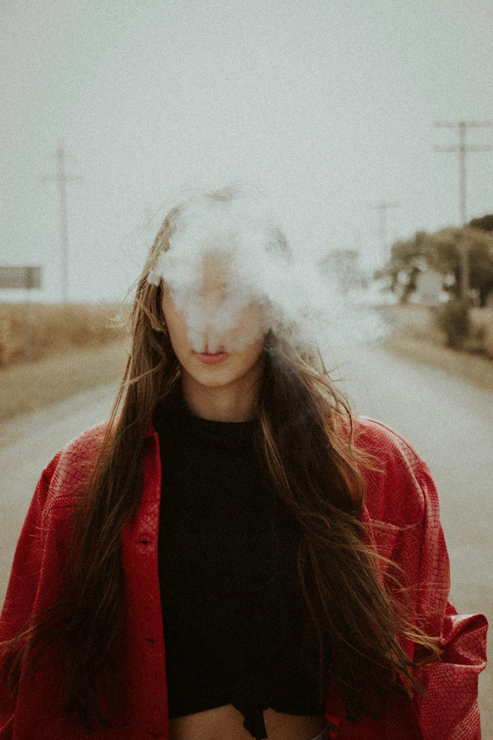 Mujer con camisa negra y chaqueta roja fumando