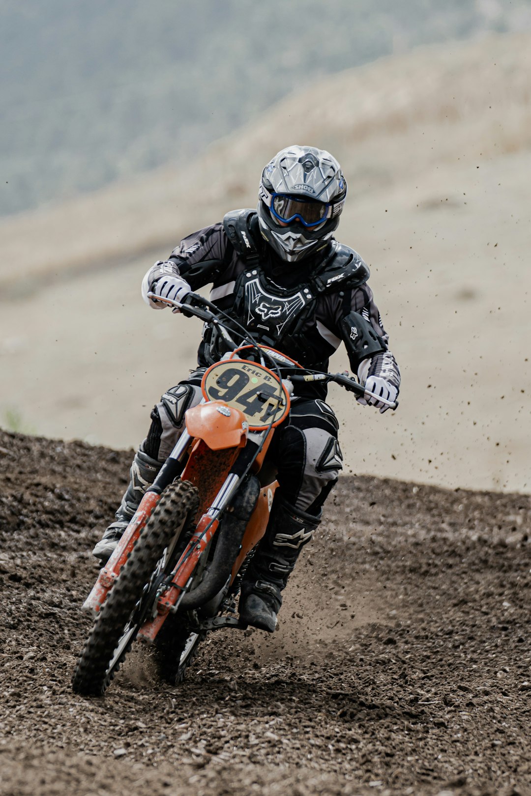 man in black and orange motorcycle suit riding orange and black motocross dirt bike