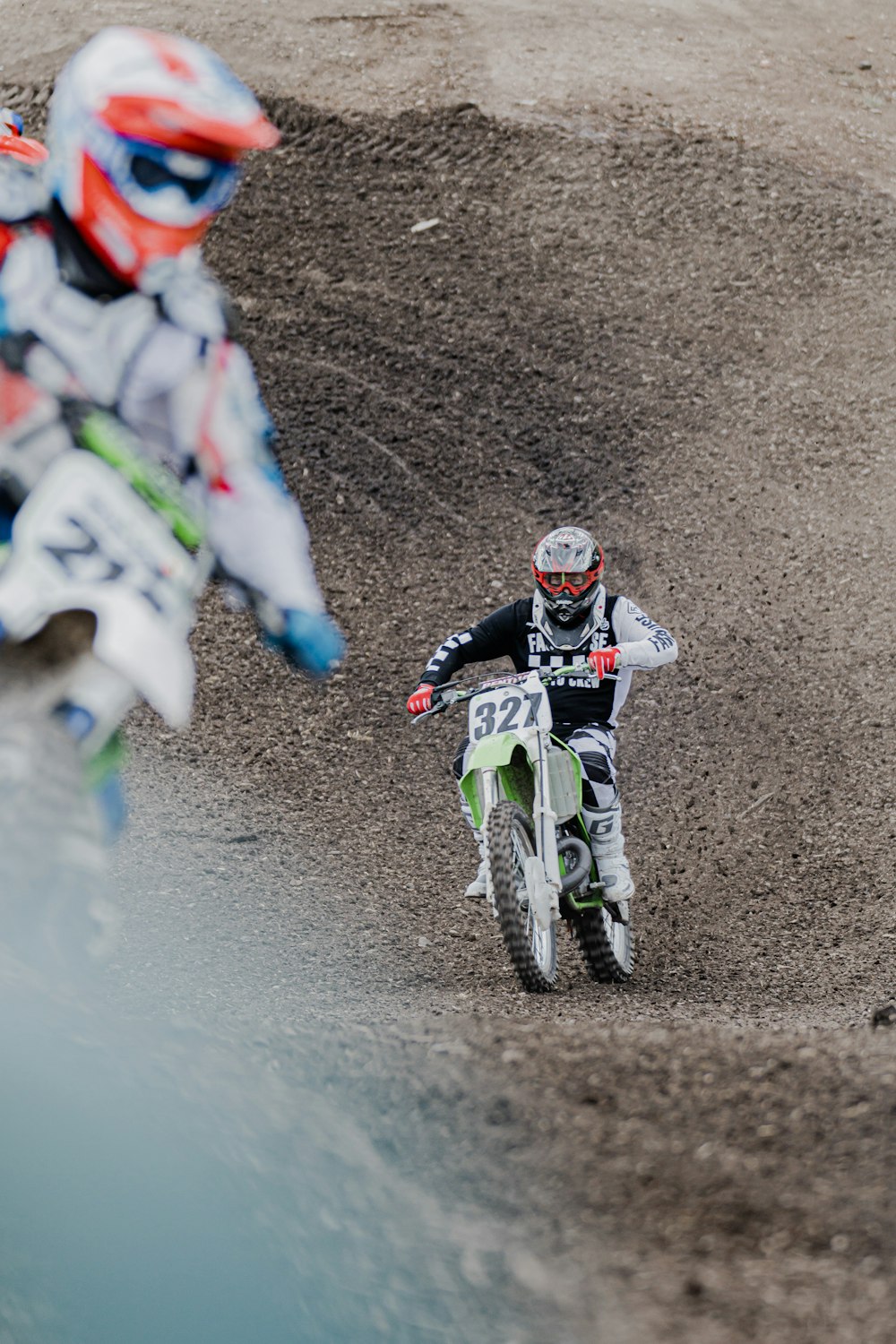 homme en costume de motocross blanc et vert conduisant une moto tout-terrain de motocross