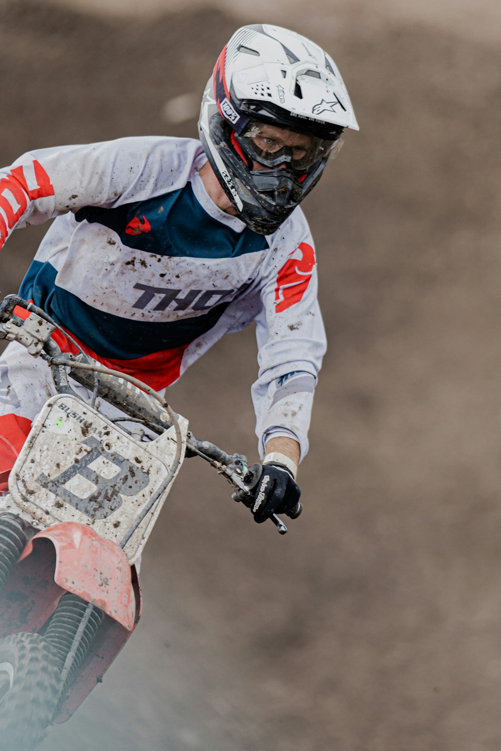 uomo in camicia a maniche lunghe bianca e rossa che cavalca su moto da cross rossa e bianca