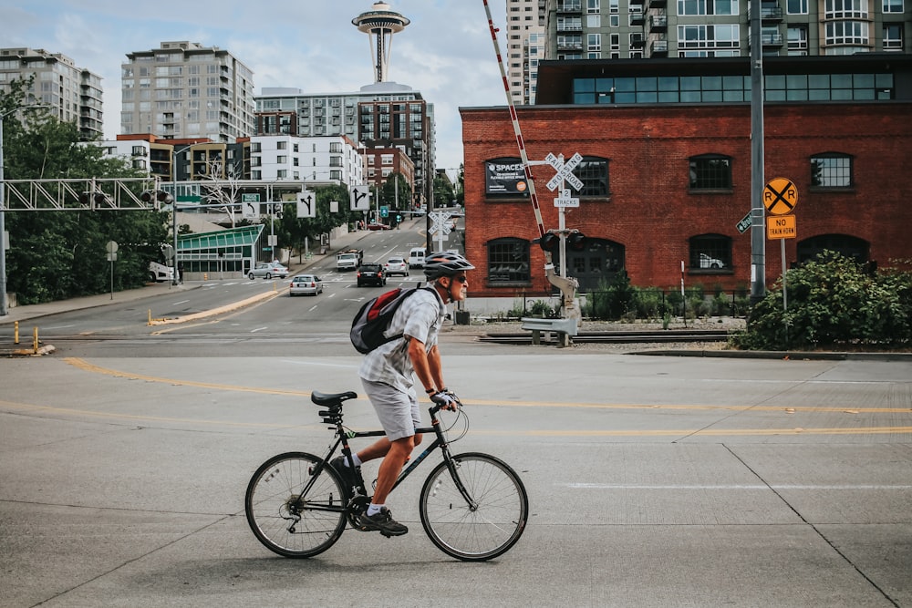 man in gray shirt riding on bicycle on road during daytime