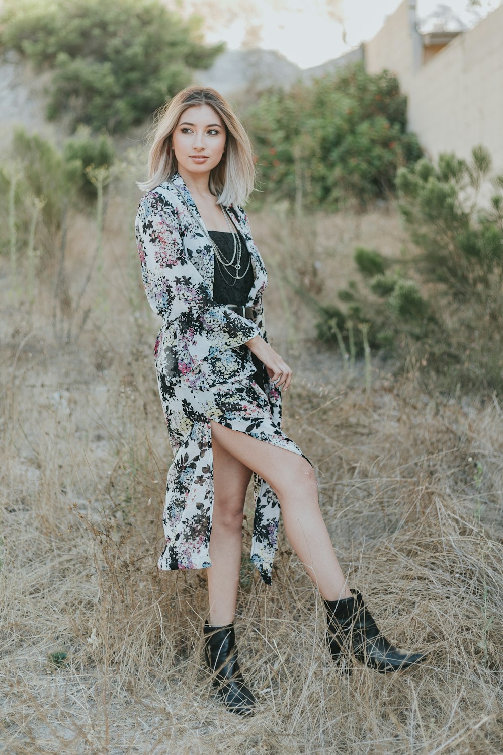 woman in black and white floral long sleeve dress standing on brown grass field during daytime
