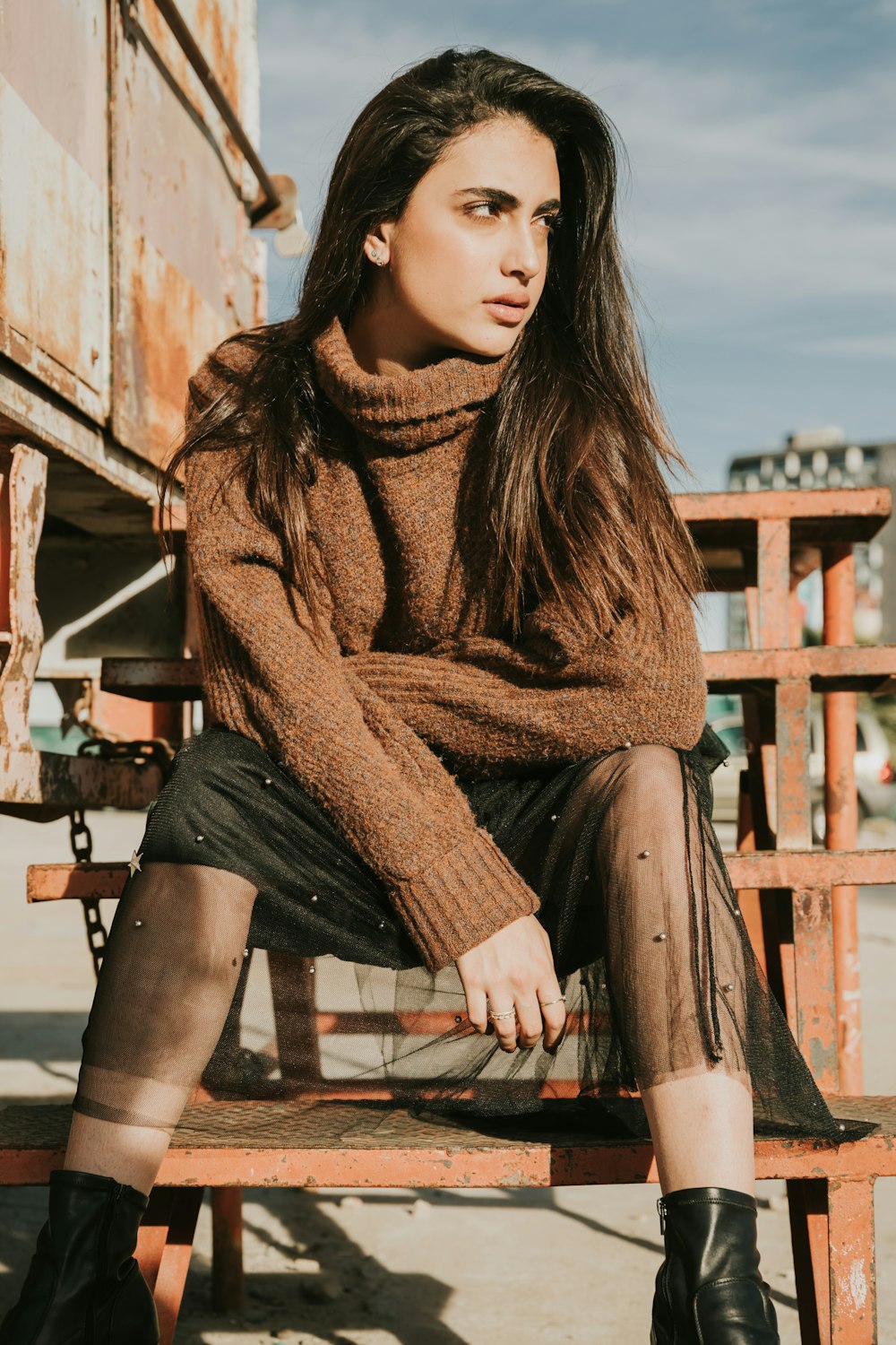 woman in brown sweater sitting on brown wooden bench during daytime