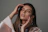 Close-up of a woman gently touching her elegantly styled ombre brows against a creamy beige background.