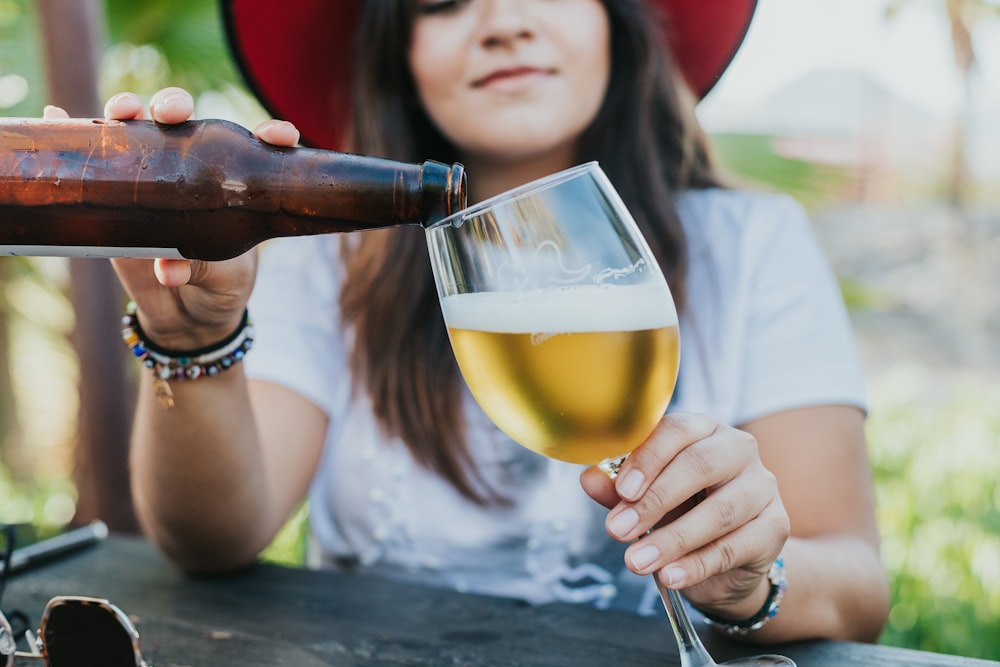 woman in white shirt holding clear wine glass with yellow liquid