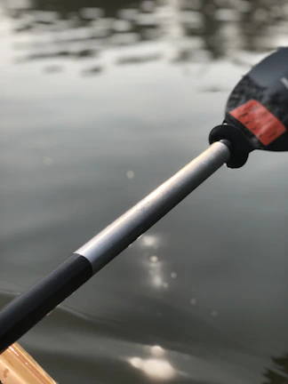 Close-up of a colorful kayak paddle cutting through sparkling river water.