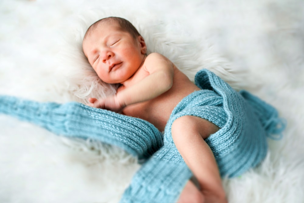 baby lying on white textile