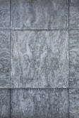 Gray textured tiles with a stone-like appearance, arranged in a grid pattern, displaying subtle variations in shading and surface texture.