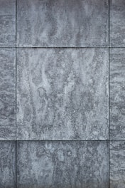 Gray textured tiles with a stone-like appearance, arranged in a grid pattern, displaying subtle variations in shading and surface texture.