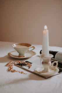 A cozy scene with layered necklaces draped over a bright ceramic dish beside a steaming cup of tea.