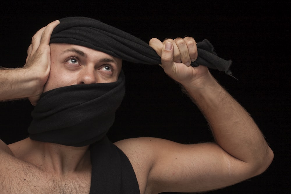woman in black tank top covering her face with black scarf