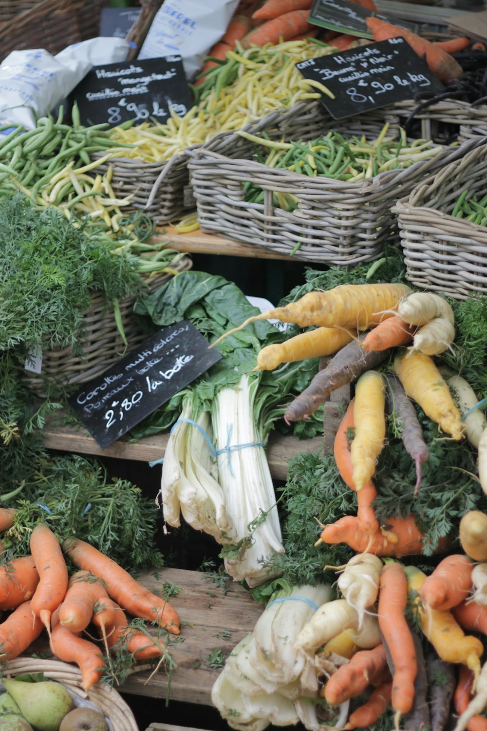 cenouras e vegetais de folhas verdes na cesta tecida marrom