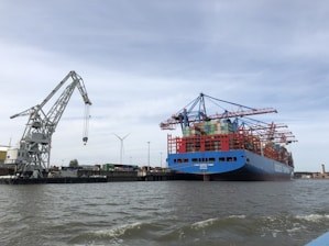 blue and red cargo ship on sea under blue sky during daytime