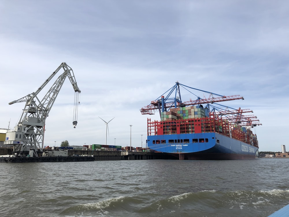 blue and red cargo ship on sea under blue sky during daytime