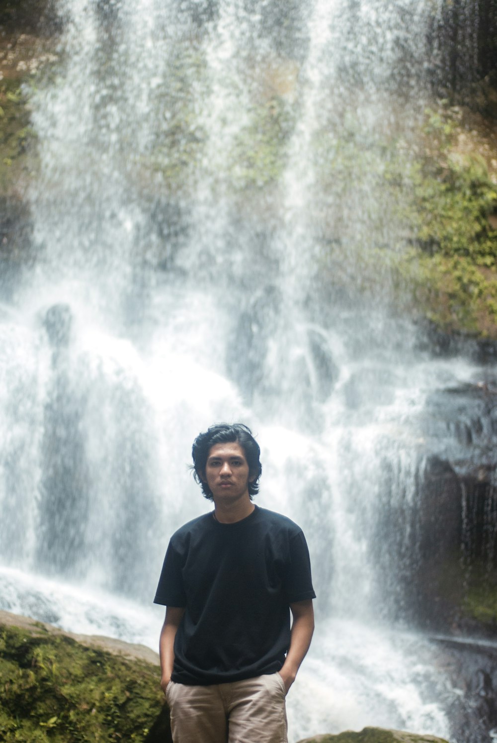 man in black crew neck shirt standing near waterfalls during daytime