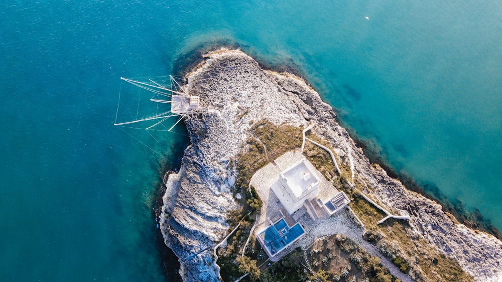 aerial view of white house on brown rock formation beside body of water during daytime