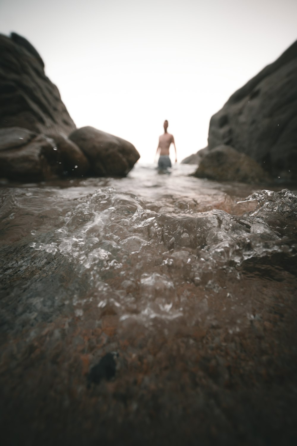 man in black shorts standing on rock formation near body of water during daytime