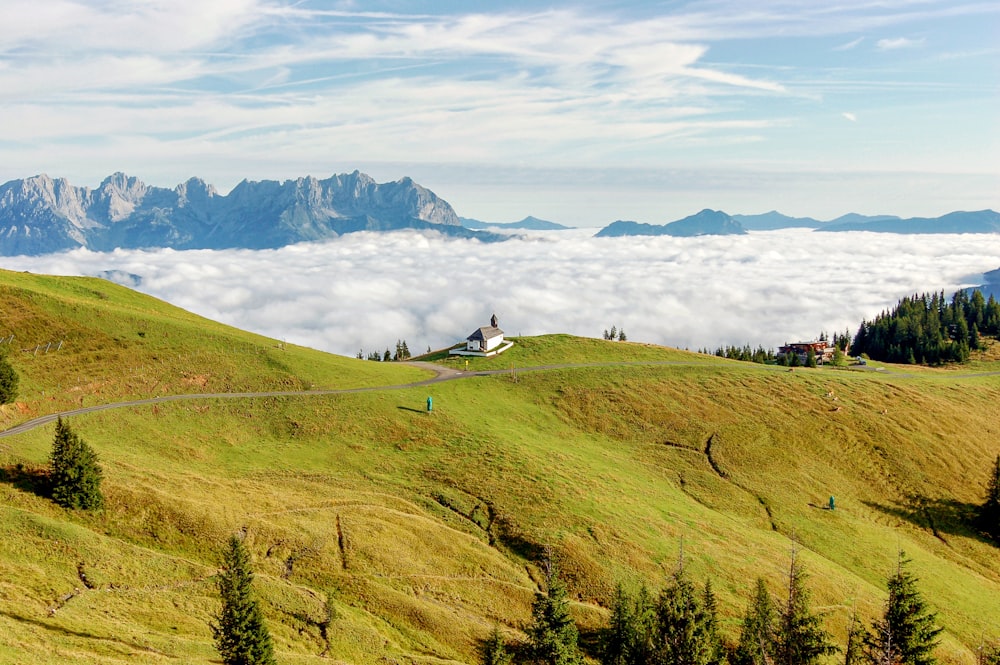 green grass field near mountains under white clouds during daytime