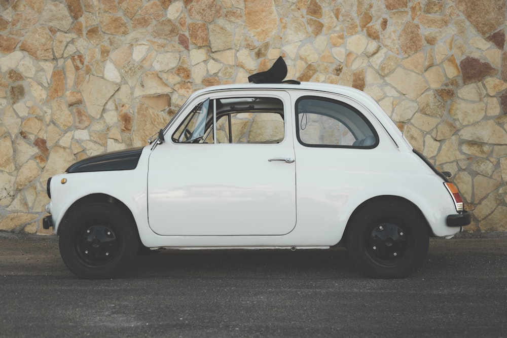 white car parked beside brown brick wall