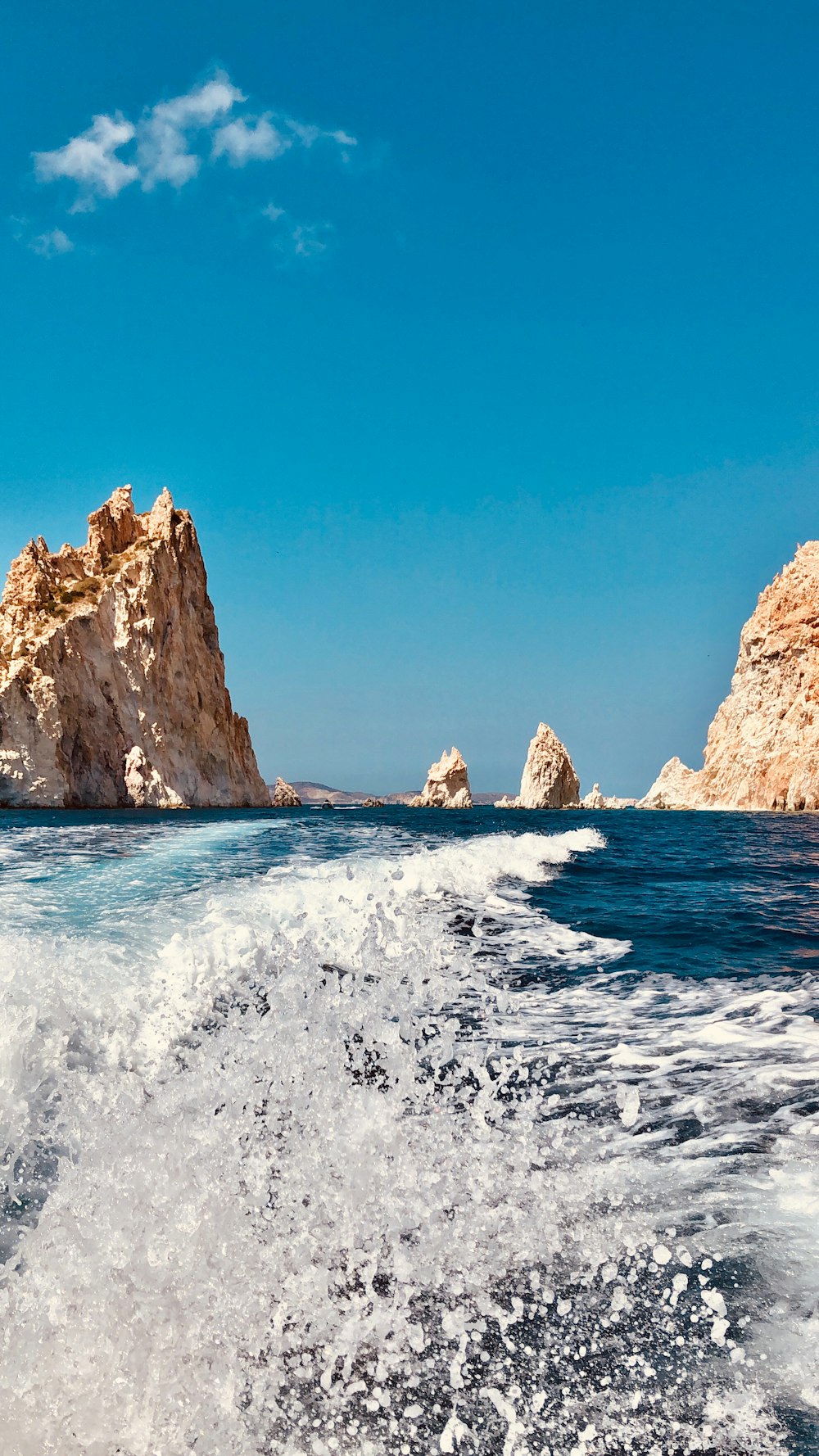 Formación rocosa marrón en el mar bajo el cielo azul durante el día