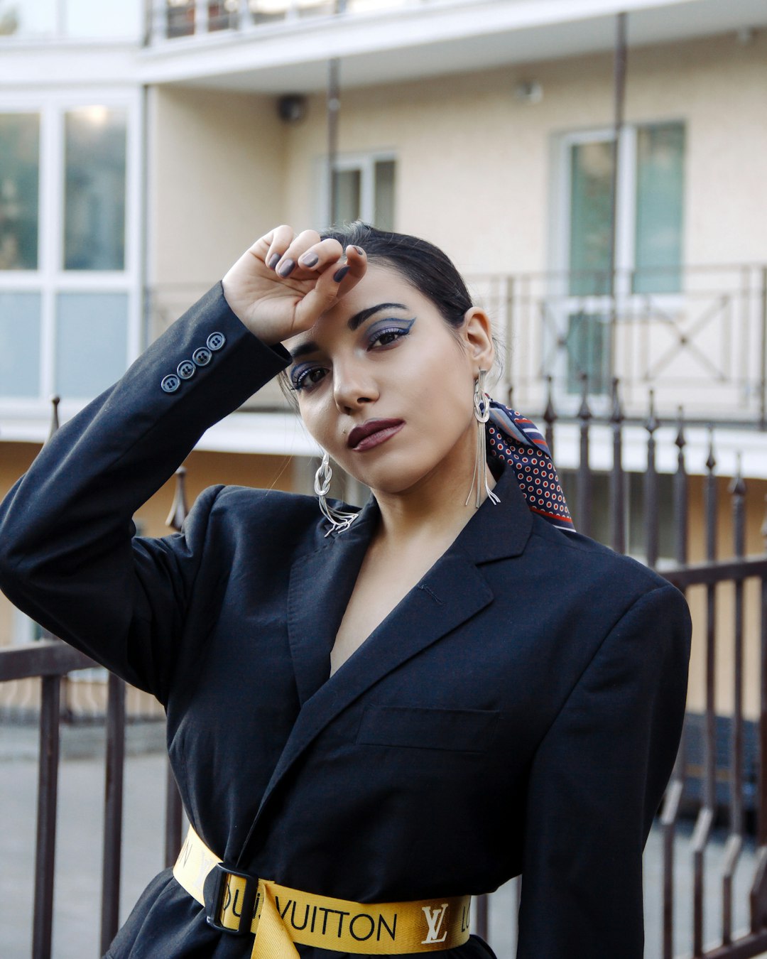 woman in black blazer standing near black metal fence during daytime