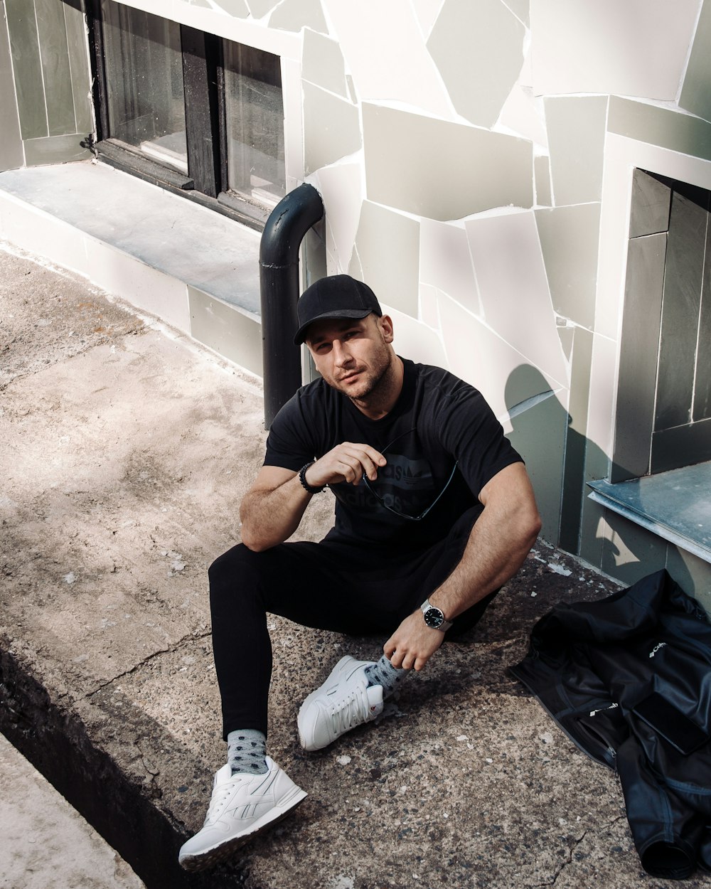 man in black crew neck t-shirt and black pants sitting on gray concrete bench