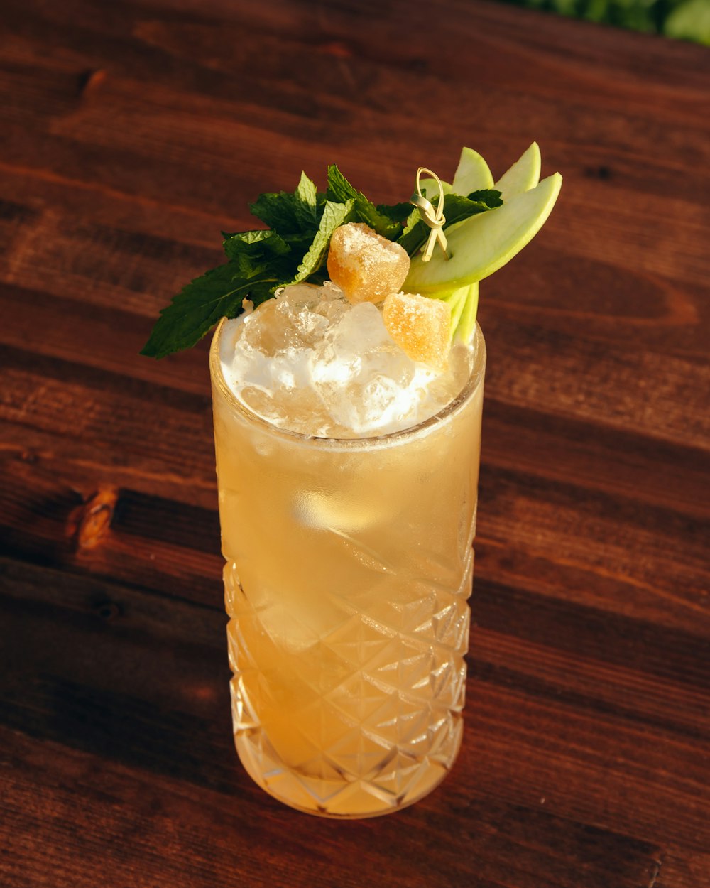 clear drinking glass with yellow liquid and green leaves