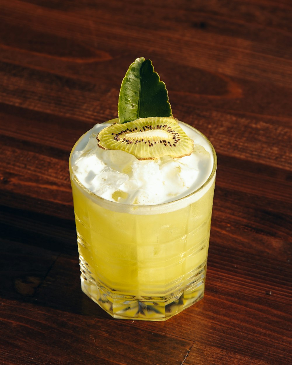 clear drinking glass with yellow liquid and green leaf