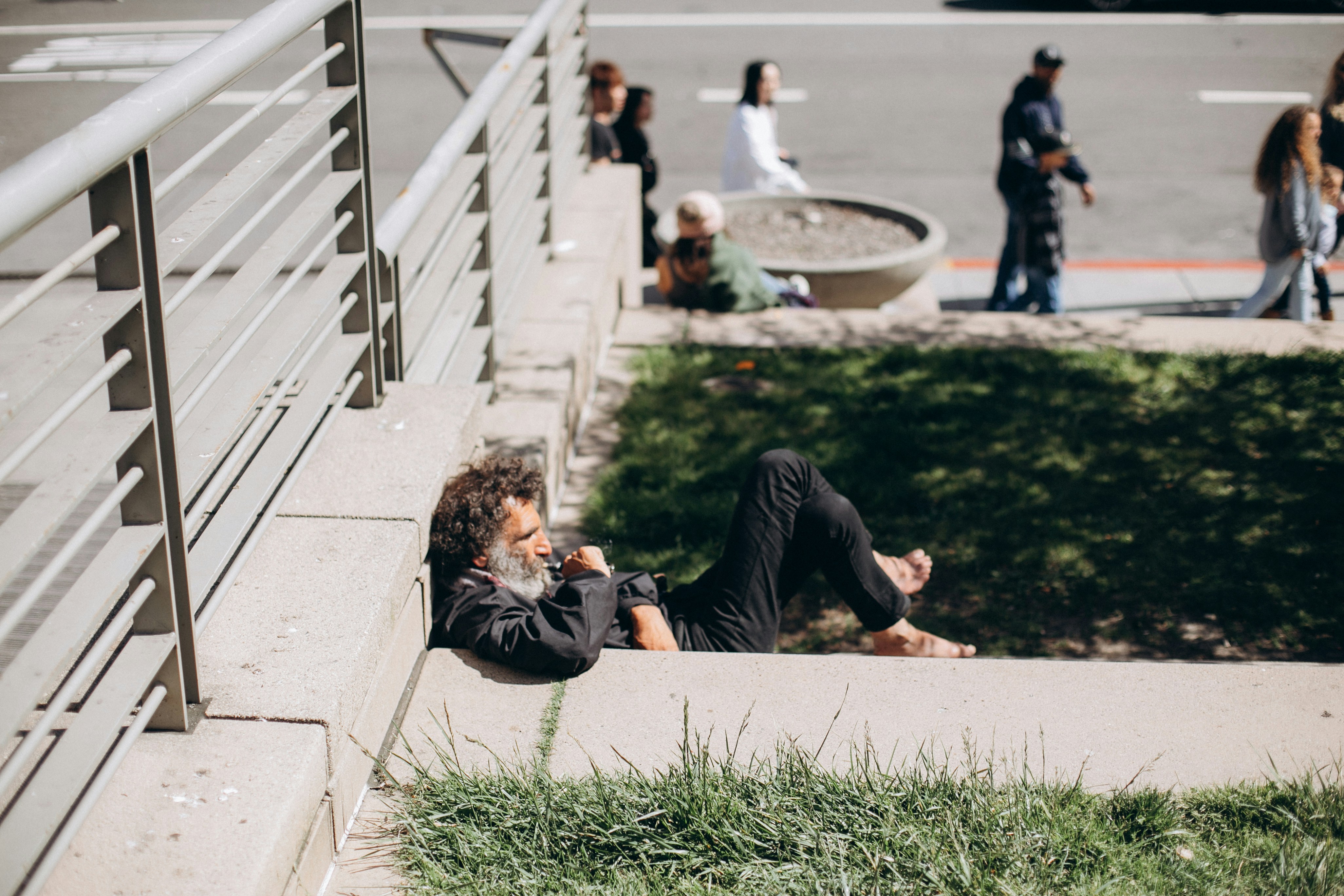 homme en chemise à manches longues noire couché sur le champ d’herbe verte pendant la journée
