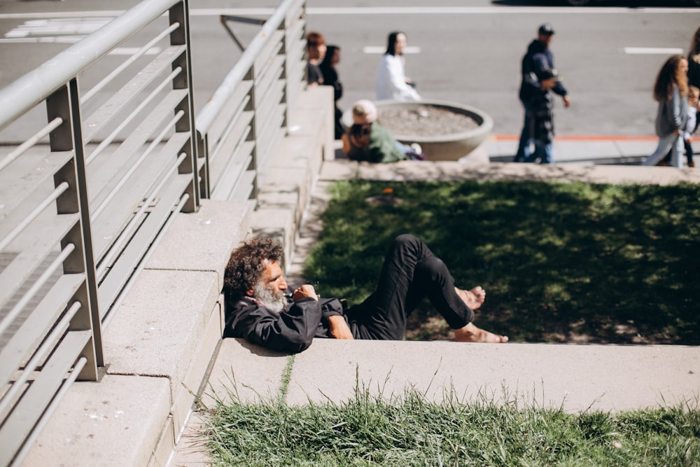 man in black long sleeve shirt lying on green grass field during daytime