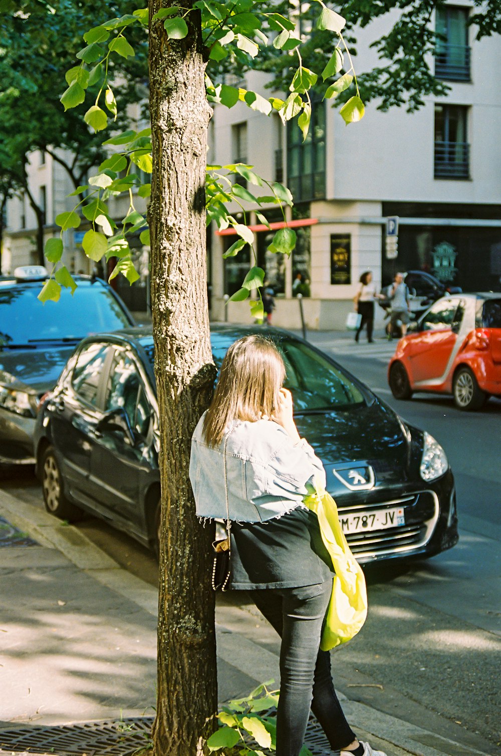 woman in white long sleeve shirt and green pants standing beside black car during daytime