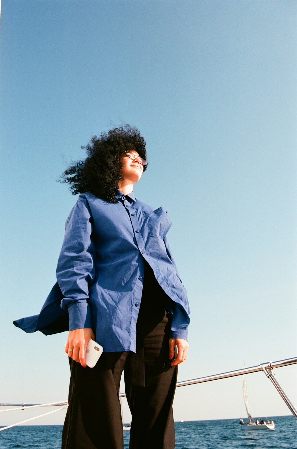 woman in black leather jacket standing on wooden dock during daytime