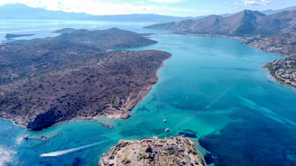 aerial view of green and brown mountains and body of water during daytime