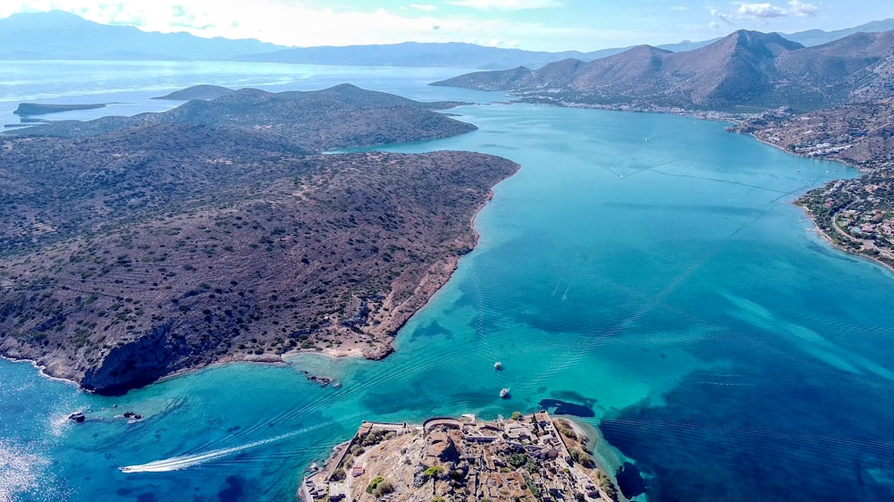 vista aérea de montanhas verdes e marrons e corpo de água durante o dia