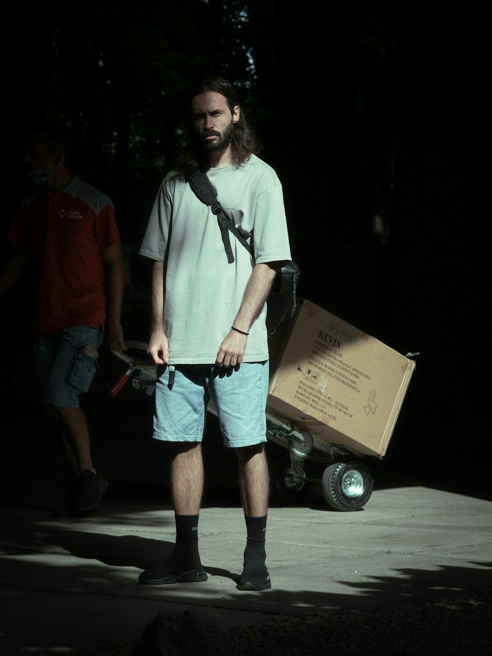 man in white shirt and blue denim shorts holding brown cardboard box