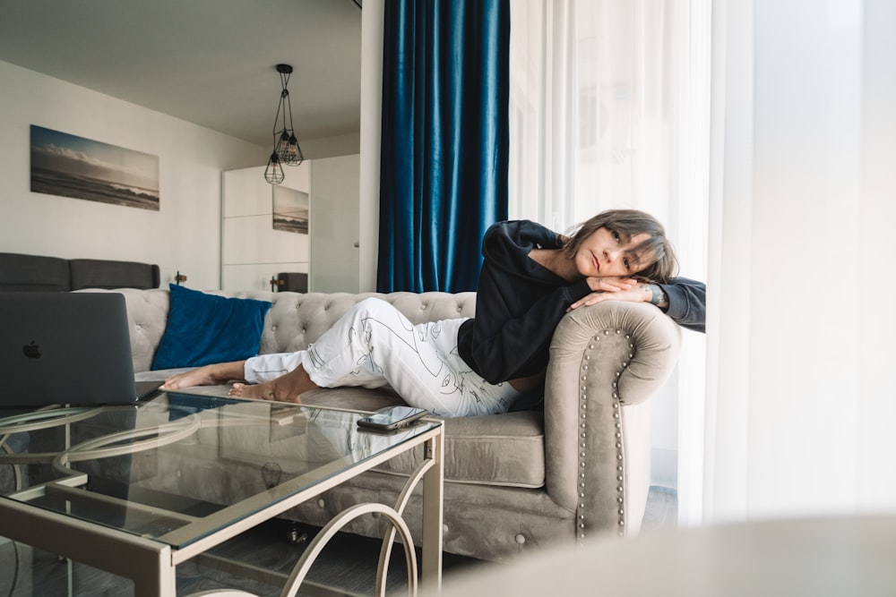 woman in gray sweater and blue denim jeans sitting on gray couch