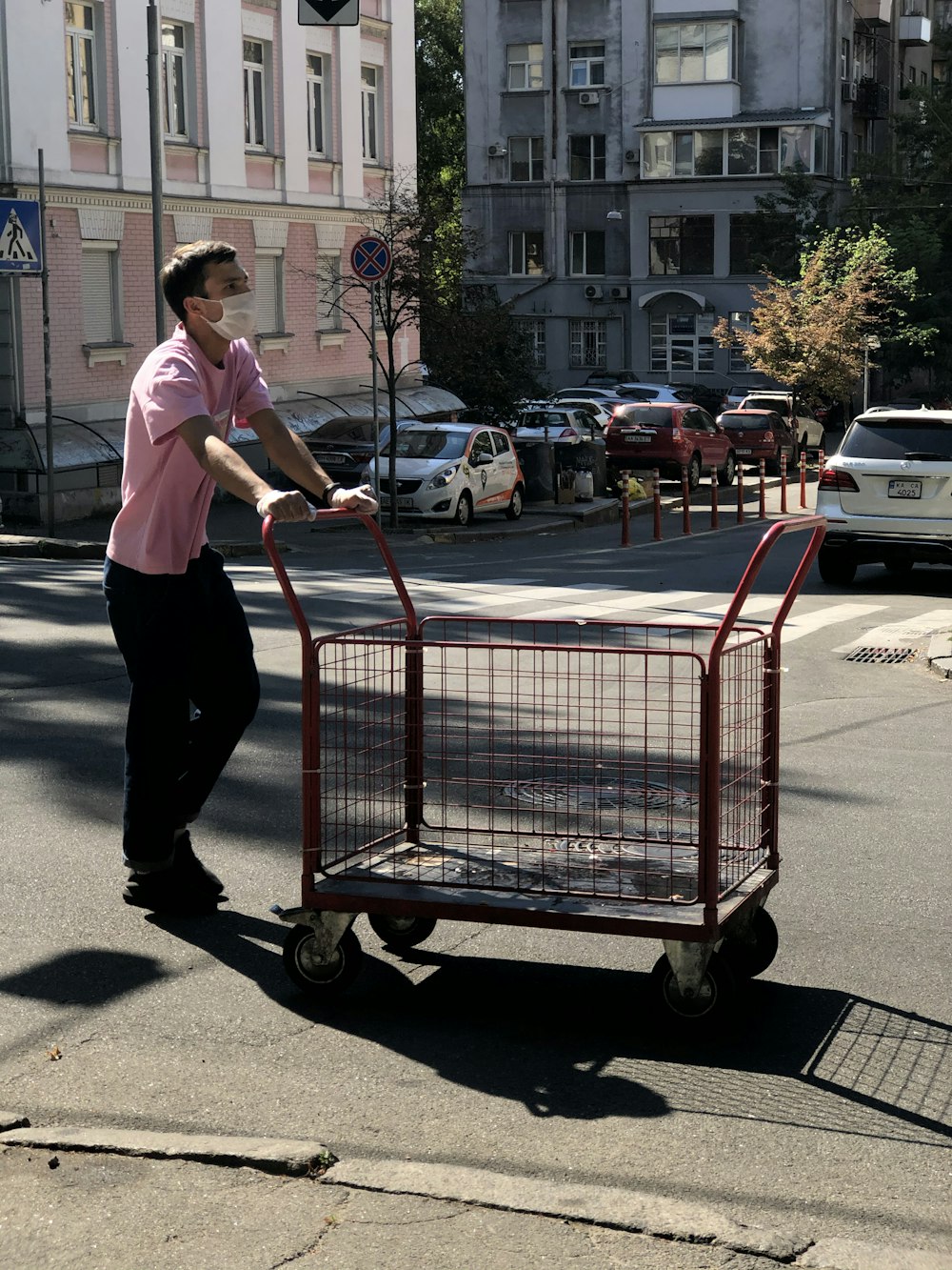 woman in white shirt and black pants holding red shopping cart