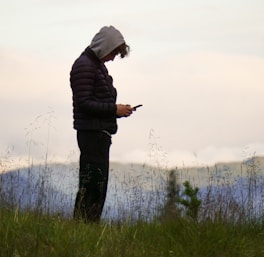 man in black jacket standing on green grass field during daytime