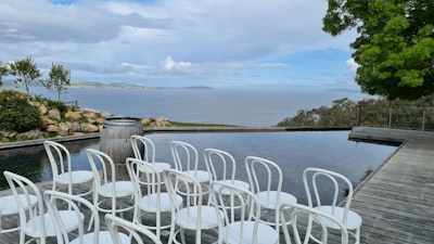 white plastic chairs near body of water during daytime occasion zoom background